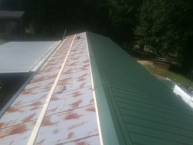 Old rusted panels beside newly installed green metal roofing — Wind Damage Roof Repair by Roofing Brothers in Berwyn