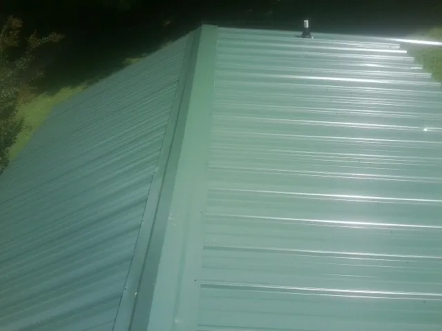 New green metal panels meeting at the ridge of a roof — Flat Roof Repair work by our crew in Berwyn