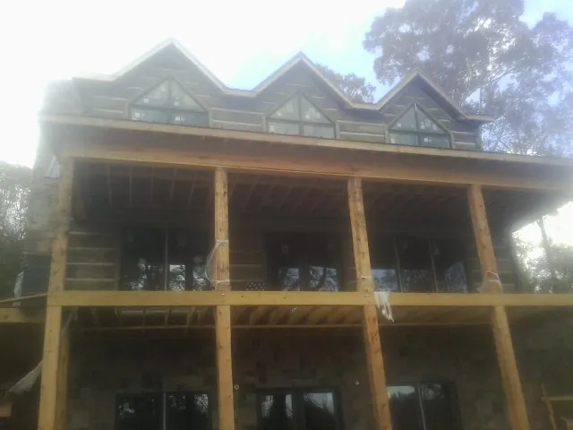 Dormers and porch framing on a large log home under construction — Roof Coating work by our crew in Berwyn
