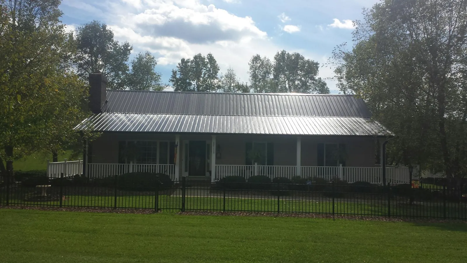 Gray metal roof on a brick ranch with a full width front porch — Gutter Guard Installation work by our crew in Berwyn